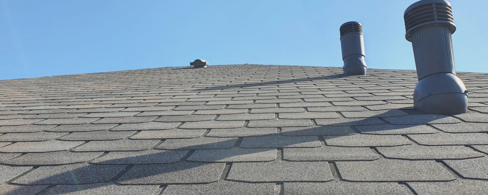 Residential asphalt shingle roof with black vent pipes installed