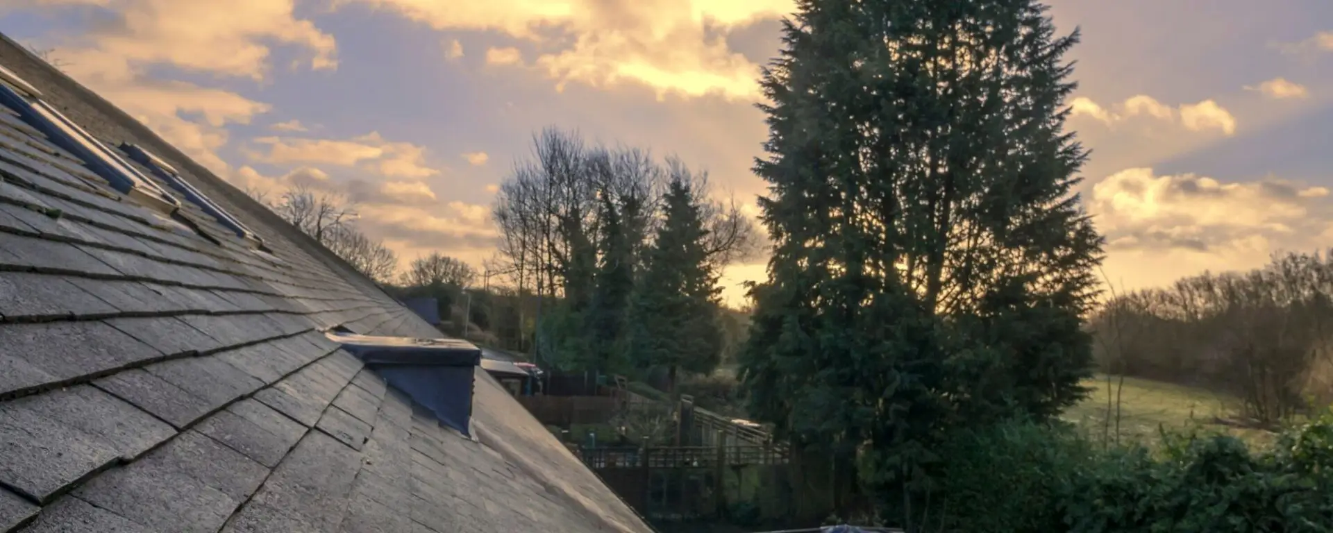 Residential roof with blue chimney overlooking rural property landscape