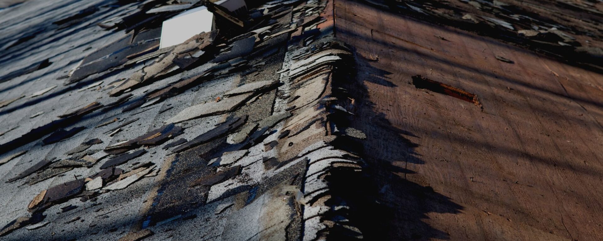 Severely damaged roof shingles with wood rot and deterioration