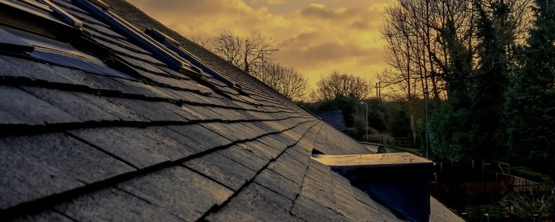 Damaged roof with missing shingles at sunset requiring repair
