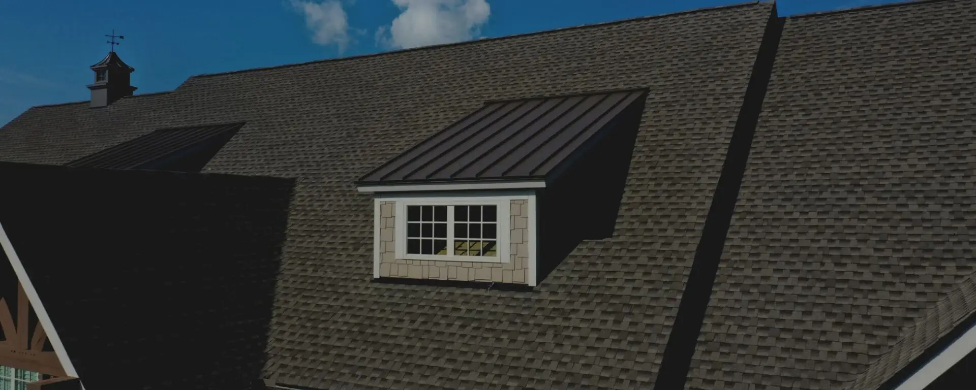 Residential roof with gray asphalt shingles and dormer window