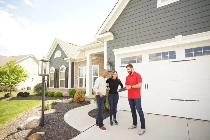 Contractor discussing a roof replacement with homeowners outside their home