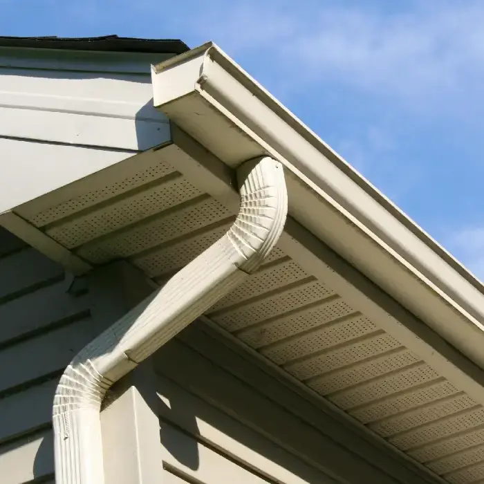 White gutter system and downspout installed on residential home eave