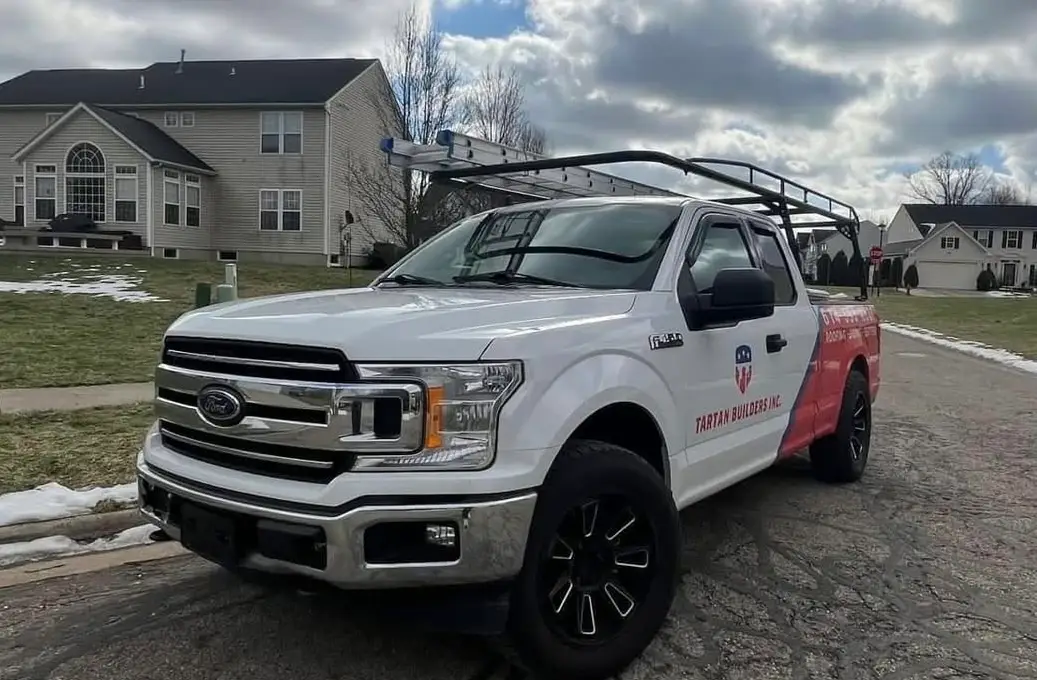 Tartan Builders white Ford pickup truck with roof rack and equipment