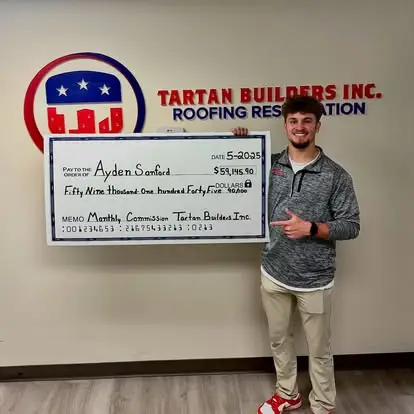 Tartan Builders employee holding large commission check