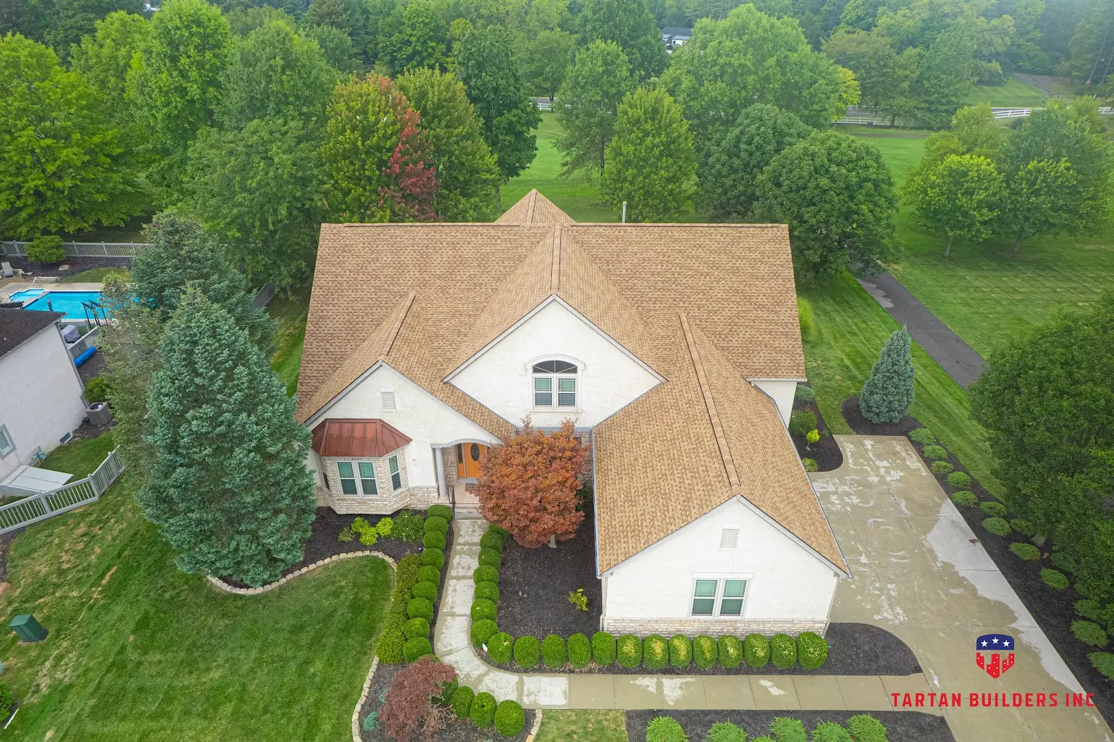 Aerial view of residential home with new tan brick roof and white siding