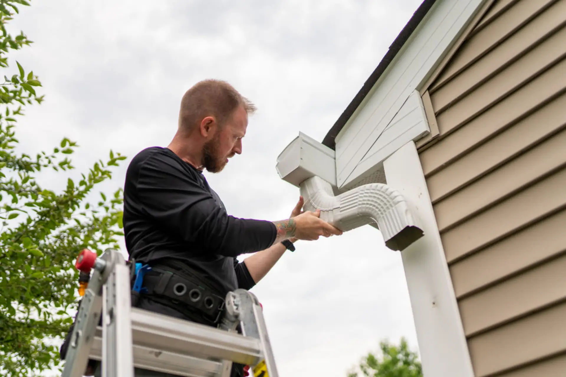 Professional installer working on a white aluminium downspout system