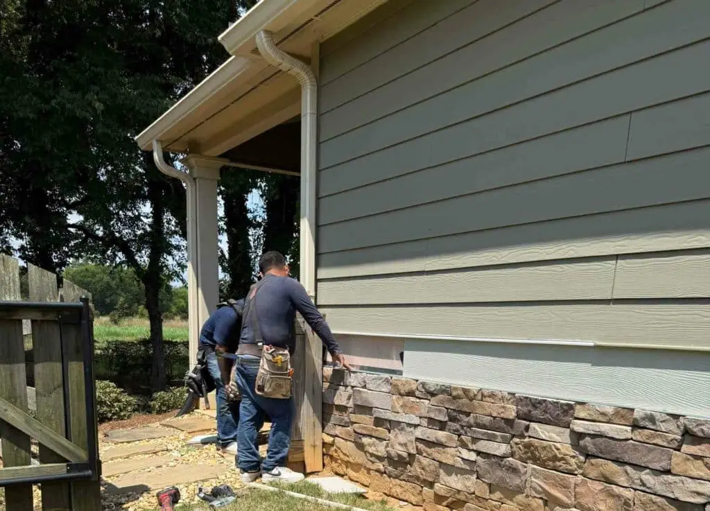 Technician installing fiber cement siding on a residential home