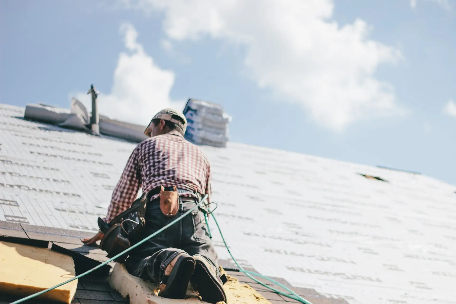 Professional roofer in safety gear installing roofing materials